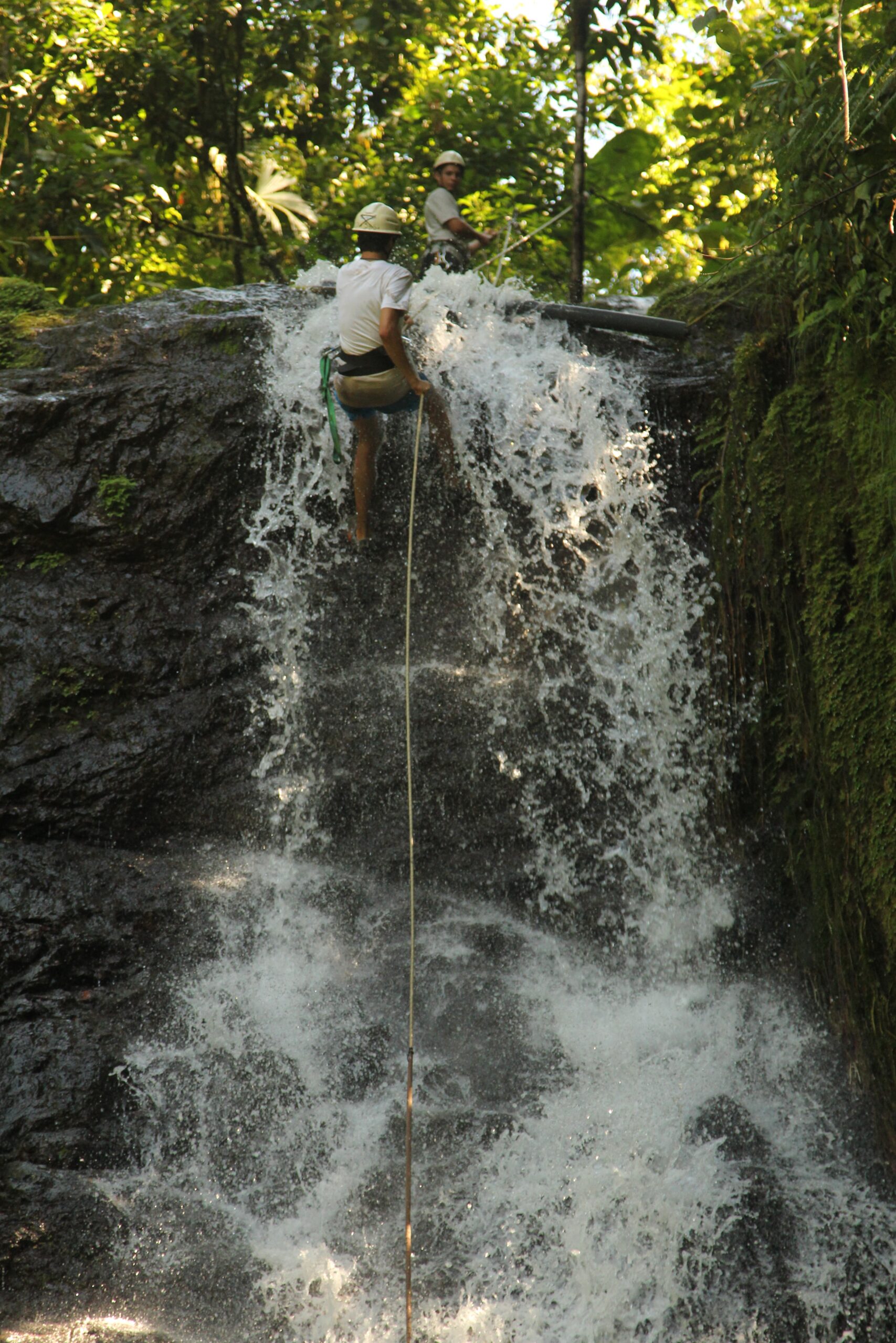 man rappelling down waterfall