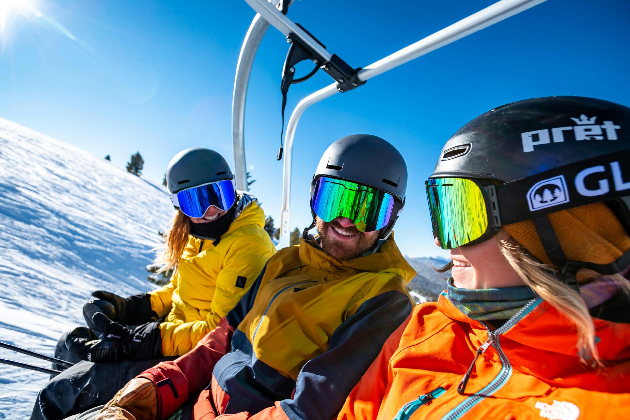 three people on chairlift, wearing goggles