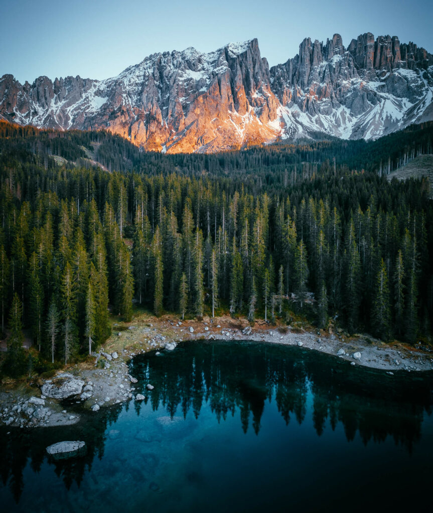 Looking over a mountain lake at dusk with light hitting the peaks in the distance.